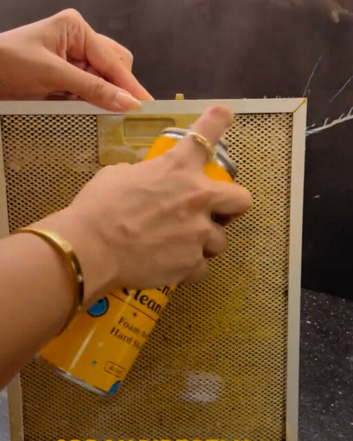 Customer spraying foam on a kitchen chimney filter