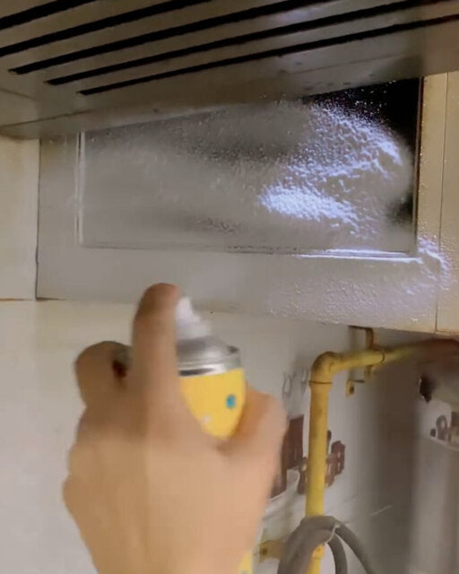Customer spraying cleaning foam beneath a kitchen chimney